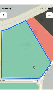 A digital map highlights a large green area outlined in blue near Aledo, TX, bordered by roads like "Alco Diona Rd" and "2301 FM 1187." A gray location pin and winding paths are visible within the green space.