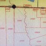 A close-up of a map showing different regions outlined in red with numerical codes like 37022, 37015, and 31651. Roads and boundaries are visible, along with a large black circle over a road near the top.