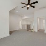 Spacious, carpeted upstairs landing area with white walls, a ceiling fan with light, stair railing, and multiple doorways leading to other rooms.