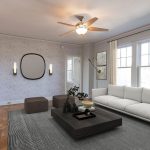 Modern living room with a white sofa, dark coffee table, neutral rug, wall mirror, ottomans, large windows with beige curtains, and a ceiling fan with lights. Minimalist decor and light walls create an airy atmosphere.