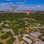 Aerial view of Fort Worth, Texas, showing the Fort Worth Zoo, Trinity River, and city skyline in the distance under a blue sky, with labeled landmarks and a red location pin on a tall building.